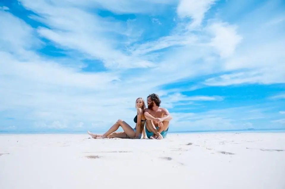 Casal sentado na areia em um dia de sol