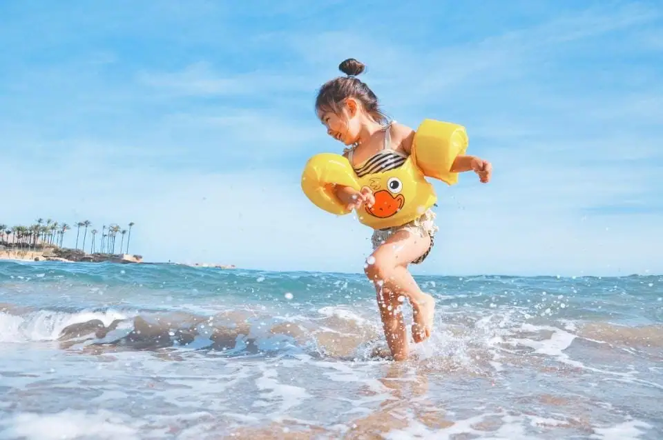 Criança brincando no mar com boias